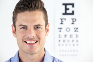 Man wearing contact lens with eye chart in background - Powered by Adobe