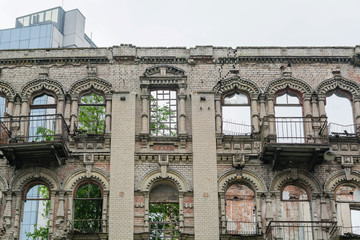 Abandoned damaged old house with blank windows against blue cloudy sky