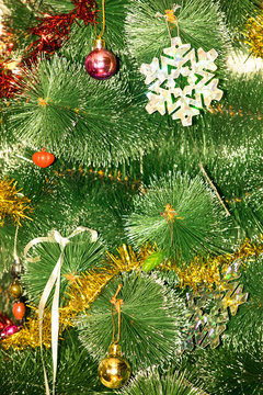 Christmas tree decorated with bright colorful toys, snowflakes. Under the tree are gifts of silver and gold gift bags and gift in a red-golden shiny packaging