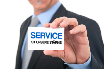 Mann zeigt Karte mit der Aufschrift: Service ist unsere Stärke
