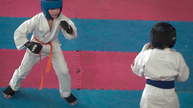 Kids karate competition. Fight a duel of teenagers. Children are protected and strikes the opponent. Young athletes are involved in a fight with courage. Slow Motion 100 FPS.