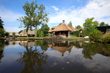 Fototapeta na wymiar A cottage with a thatched roof in the village of Giethoorn in The Netherlands during a beautiful summer morning.