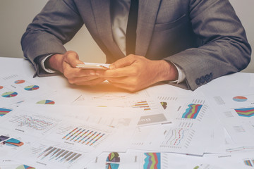businessman working on cell phone over business report papers,da