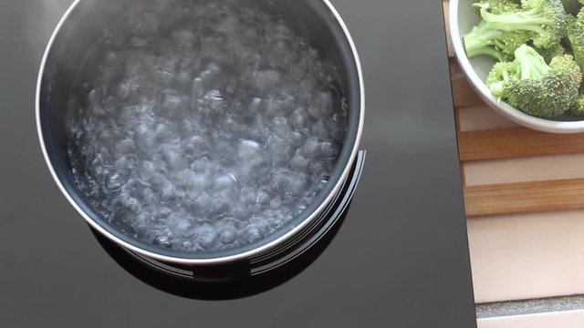 Boiling water at pan on Induction stove top panel, closeup