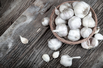 Fresh organic garlic in wicker basket on rustic table