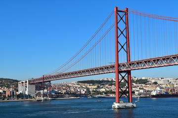 The 25 de Abril Bridge, a red bridge connecting the city of Lisbon, capital of Portugal, to  Almada on the left bank of the Tejo river.