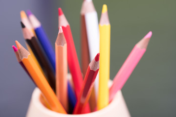 Fototapeta premium Color pencils on the table in the container with background lights. Colorful pencils in a variety of colors. Back to school concept. Closeup. Selective focus.