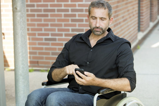 man in wheelchair texting on his phone