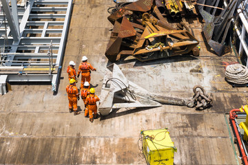 Offshore workers handling anchor to be lifted for deployment on construction barge at offshore Terengganu, Malaysia