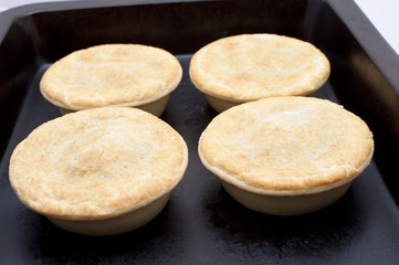 Four meat pies on a baking tray