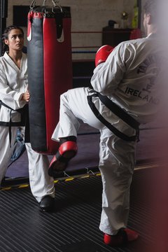 Man and woman practicing karate with punching bag