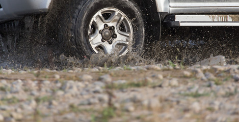 Car wheel in a spray of dirt and water