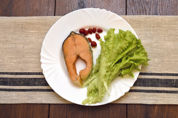 Dish with slice of fried salmon, salad and spicy pepper
