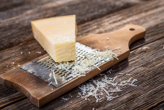 Grated parmesan cheese and  grater on wooden background