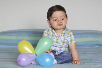 pensive baby sitting with balloons