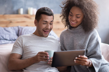 Laughing couple watching a film in the bedroom