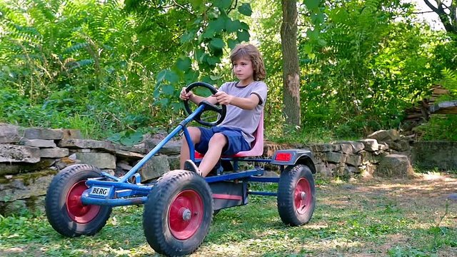 Slow motion of young boy driving kart in the courtyard of an old house
