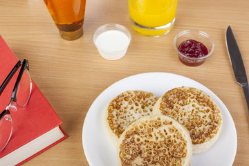 Crumpets on a plate with a book and reading glasses