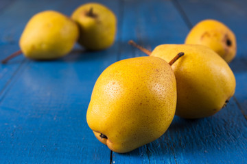 Fresh ripe organic yello pears on blue rustic wooden table, natural background, diet food.
