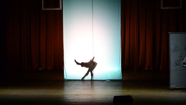 The dancer dances behind a white background, dance of a shadow.