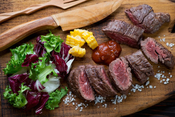 Sliced medium rare grilled machete beefsteak with salad, closeup