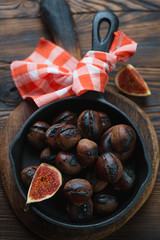 Cast-iron frying pan with roasted chestnuts and fig fruits