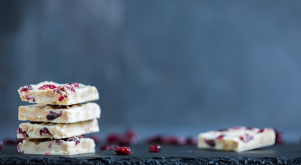 Selbstgemachte, weiße Schokolade mit Cranberries auf schwarzer Steinplatte mit Textfreiraum