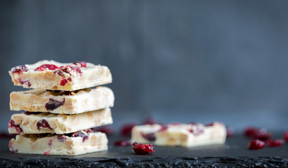Hausgemachte, weiße Schokolade mit Cranberries auf dunkler Schieferplatte