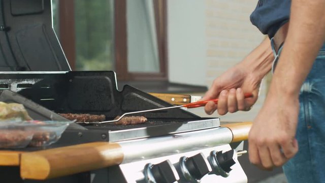 Man Flipping Burgers on Grill