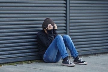 young homeless boy sleeping on the street