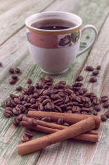 Cinnamon sticks on coffee beans with coffee cup on old rustic background