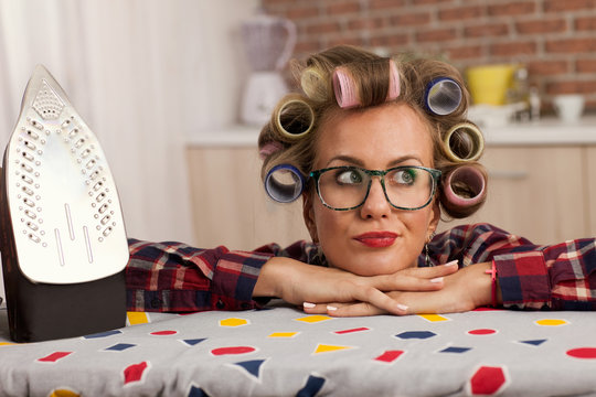 Funny woman with curlers cleaning ironing ,having fun during spr