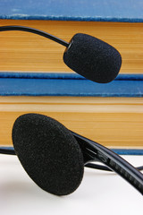 Headphones with a microphone and a stack of books on white backg
