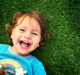 smiling little girl laying on the grass top view