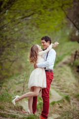 Fototapeta premium Lure lady hangs on man's neck while they stand in the park