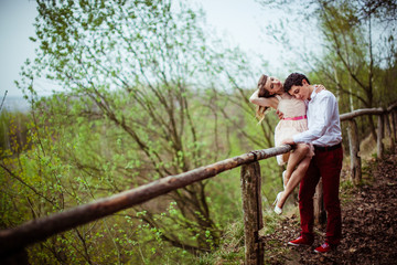 Man leans to woman's chest while holding her on wooden fence in