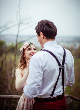 Radiant woman in flower wreath looks at her man in braces