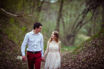 Naklejka premium Tall man admires his lady in peach dress while walking in the pa