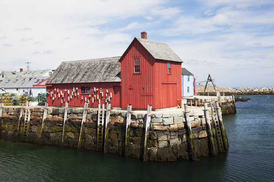 A red building on a pier at the water's edge;Rockport massachusetts united states of america
