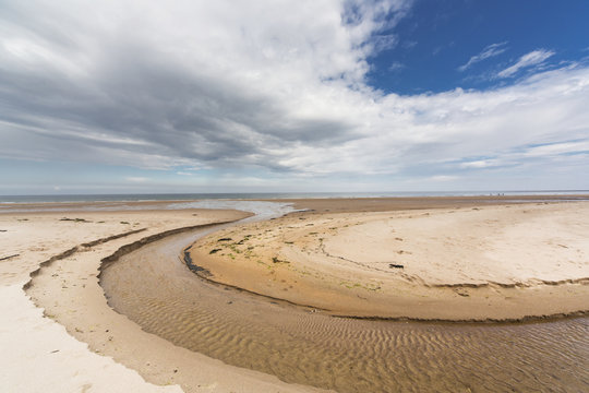A stream formed in a circular shape in the sand along the coast;Druridge bay northumberland england