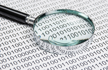 magnifying glass on a binary code