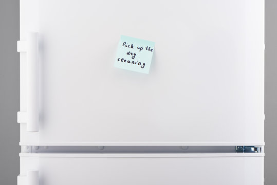 Pick up dry cleaning on blue notepaper on white refrigerator