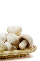 White Button Mushrooms – White button mushrooms piled on a wicker plate. White background.