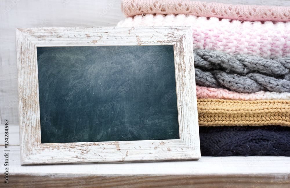 Sticker Stack of knitwear on wooden table empty frame background.