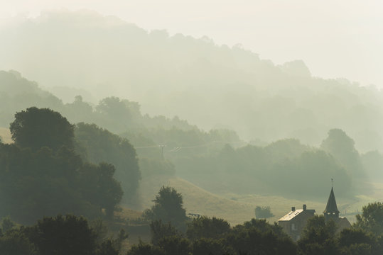 Church and house of Le Vey on misty morning, near Clecy; Swiss Normandy, Normandy, France