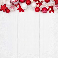 Red and white Christmas ornament top border with snow frame on a white wood background