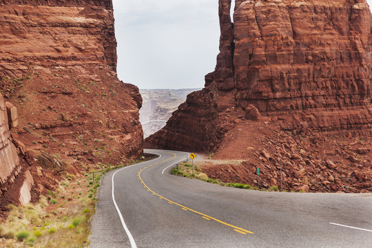 Highway 95 West Of Hite, Utah As The Road Drops Down Between Two Red Sandstone Formations To The Colorado River; Utah, United States Of America
