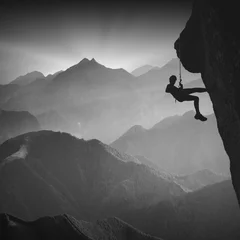 Foto op Aluminium Climber on a cliff against misty mountains. Monochrome © Bashkatov
