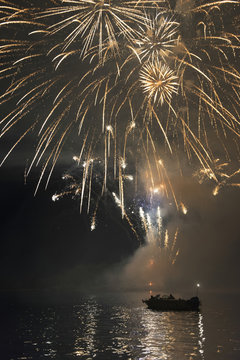 Fireworks display over a lake illuminating the boats on the water; Kenora, Ontario, Canada