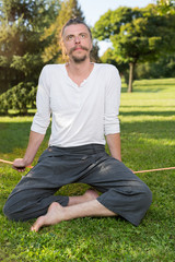 Fototapeta premium portrait of man sitting on slackline and balancing on a rope